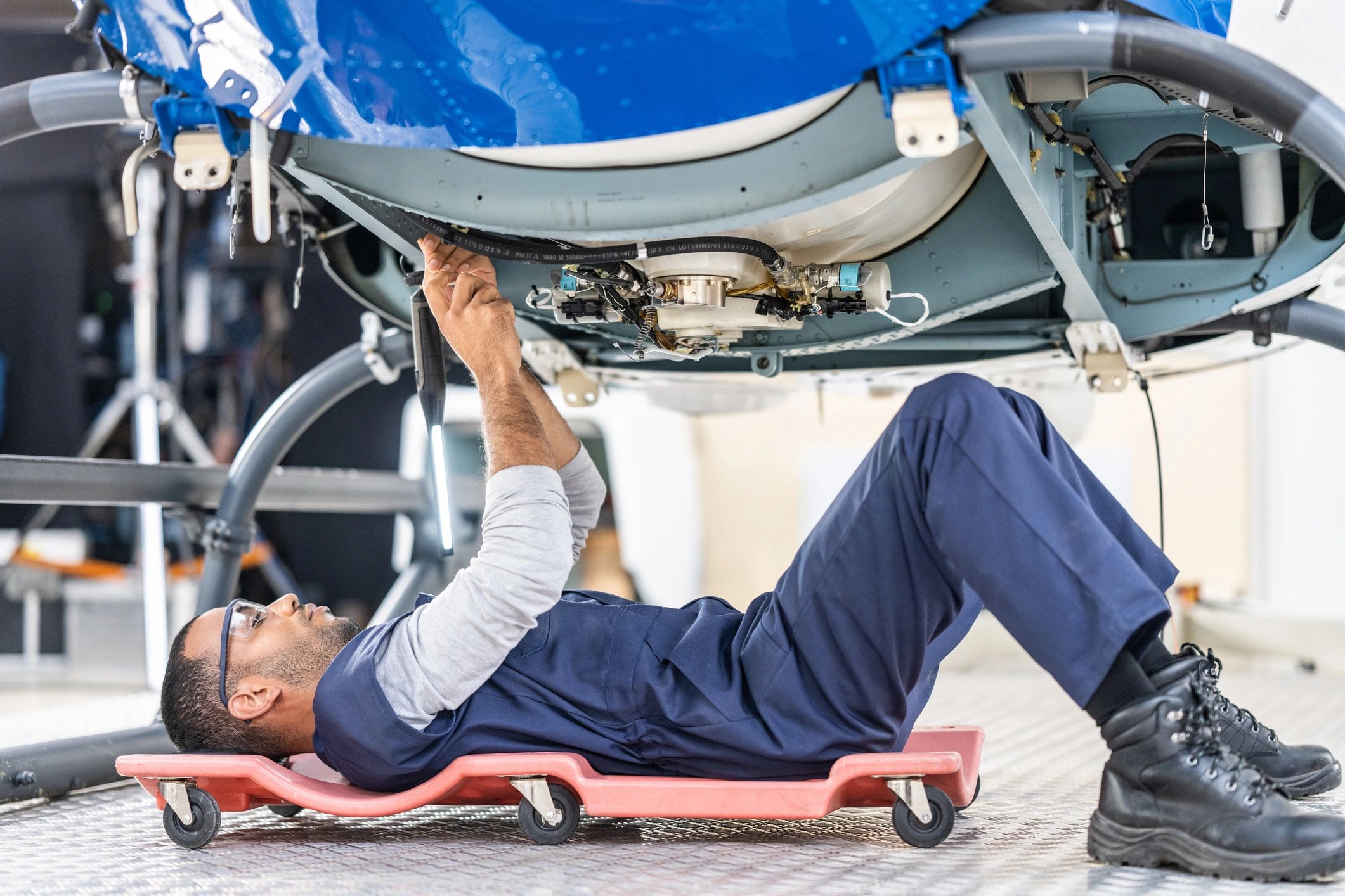 Technician working underneath a vehicle to inspect for leaks