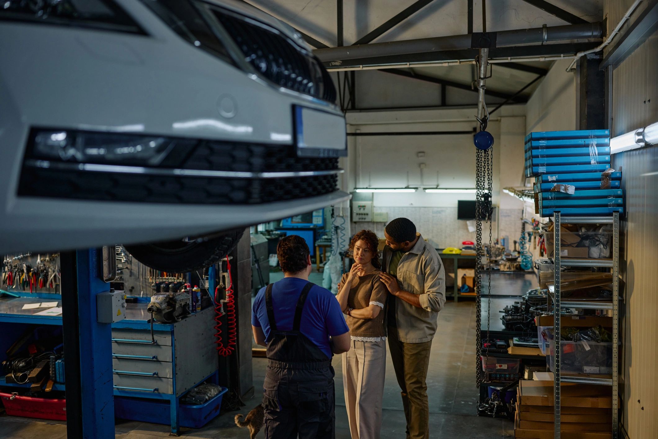 Customers speaking with a mechanic in a well-lit auto repair garage